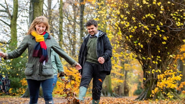 Two visitors walking through a woodland in the autumn
